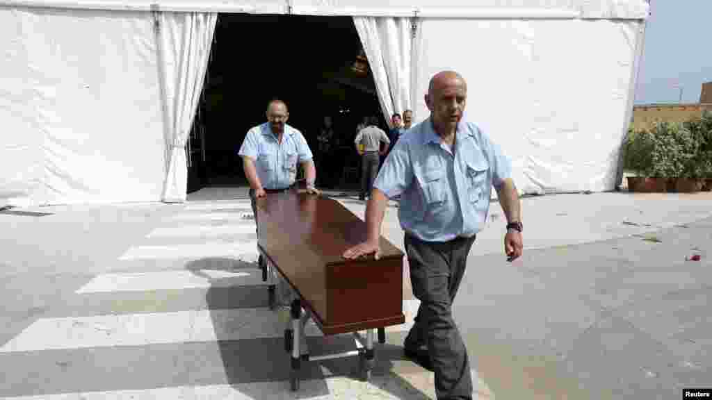 Le personnel hospitalier coniot, vers un corbillard, un cercueil contenant le corps d'une victime au terme d’un service funéraire interreligieux tenu pour les quelques-uns des 900 migrants morts dans l'une des pires catastrophes maritimes, à l'hôpital Mater Dei à Tal-Qroqq, le 23 avril 2015. 