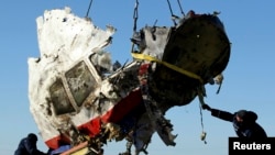FILE - Local workers haul away a piece of wreckage of Malaysia Airlines flight MH17 at the site of the plane's crash near the village of Hrabove, Donetsk region, eastern Ukraine, Nov. 20, 2014.