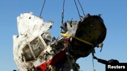 FILE - Local workers transport a piece of the Malaysia Airlines flight MH17 wreckage at the site of the plane crash near the village of Hrabove (Grabovo) in Donetsk region, eastern Ukraine, Nov. 20, 2014.