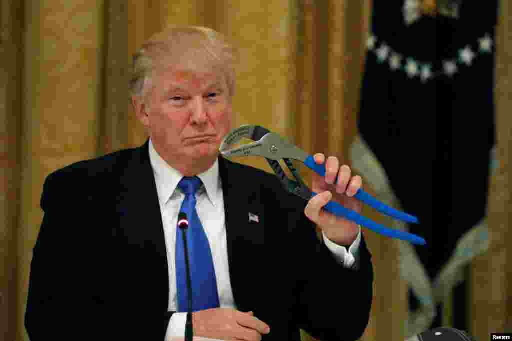 U.S. President Donald Trump holds a mechanical tool as he attends a Made in America roundtable in the East Room of the White House in Washington, DC.