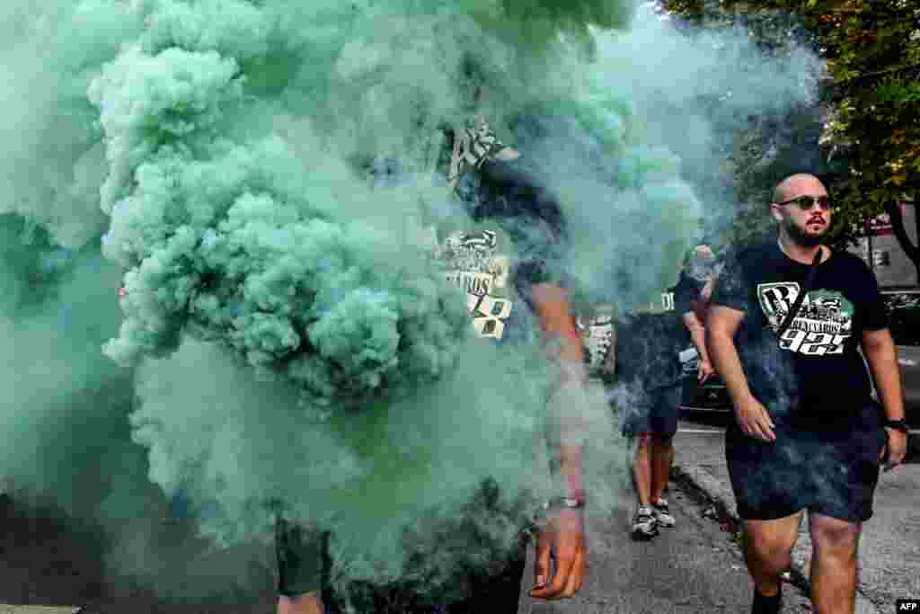 A man walks in flare smoke as he arrives with some fellow supporters of Hungarian football club Ferencvaros at the Maksimir Stadium in Zagreb, August 6, 2019, to attend the UEFA Champions League play off football match against Dinamo Zagreb, Croatia.