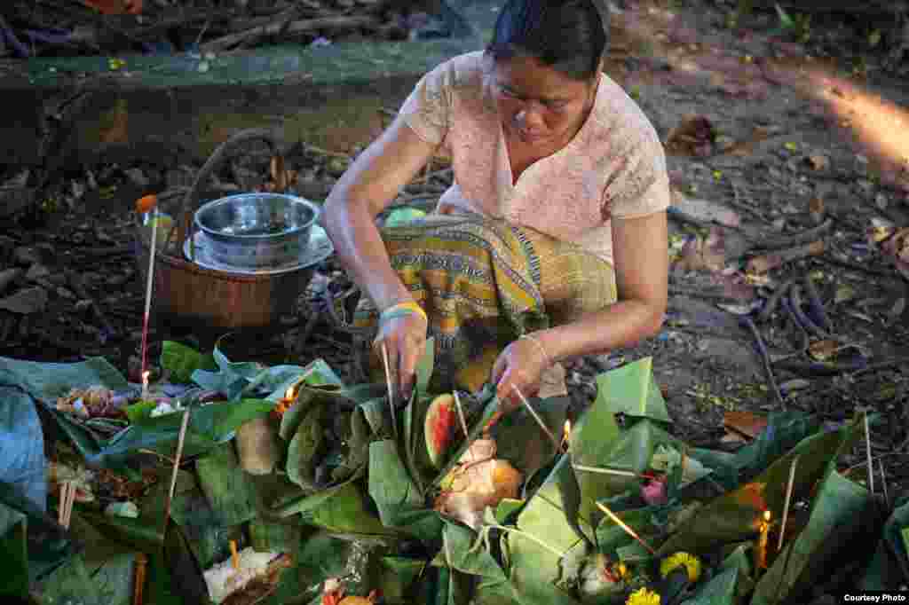 Banana leaves filled with offerings of food are placed at the base of a tree during the annual northeast Thai festival of Boon Khao Pradub Din, Thailand, Aug. 24, 2014. The ritual pays homage and respect to the earth and soil and the spirits of departed loved ones. (Photo taken by Matthew Richards/Thailand/VOA reader)