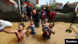 Người dân nhận tiền cứu trợ từ những người làm từ thiện tại vùng lũ ở tỉnh Quảng Trị hôm 23/10. Việt Nam vừa đề xuất xóa bỏ tên bão Linfa gây trận lụt lịch sử ở miền Trung vừa qua để tránh gợi lại "đau buồn."