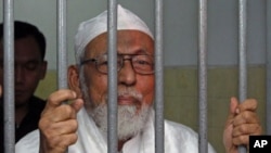 Indonesian militant cleric Abu Bakar Bashir - jailed for 15 years for his involvement with a group that aimed to kill the country's president - speaks to journalists while he waits inside a cell before his trial at South Jakarta court, June 16, 2011