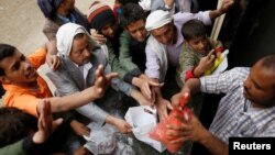 FILE - People gather to collect food rations at a food distribution center in Sana'a, Yemen, March 21, 2017.