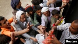 FILE - People gather to collect food rations at a food distribution center in Sana'a, Yemen, March 21, 2017.