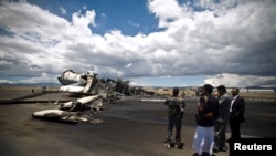 Airport officials look at the wreckage of a military transport aircraft destroyed by Saudi-led airstrikes, at the Sanaa International Airport, in Yemen, May 5, 2015.