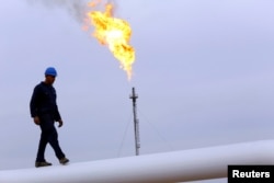 FILE - A worker walks on an oil pipeline at Khurmala oil field on the outskirts of the city of Arbil, in Iraq's Kurdistan region, Dec. 4, 2013.