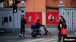 시진핑(왼쪽) 중국 국가주석과 마오쩌둥 전 국가주석 겸 혁명군사위원회 주석의 얼굴이 나란히 보이는 상하이 시 공공기관 출입문 앞으로 시민들이 지나고 있다. (자료사진)