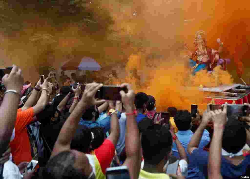 Devotees flock to catch a glimpse of an idol of the Hindu God Ganesh, the deity of prosperity, as it leaves a workshop ahead of the Ganesh Chaturthi festival in Mumbai, India.