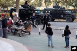 Residents watch a convoy of security personnel and armored vehicles in a show of force through central Kashgar in western China's Xinjiang region, Nov. 5, 2017.