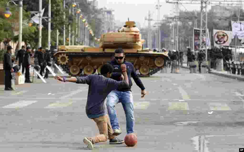 Protesters play with a ball in front of a tank securing the area around the presidential palace in Cairo, Egypt, Dec. 14, 2012.