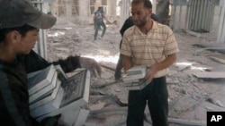 Residents of Qusair, Syria salvage copies of the Quran from a mosque bombed by government forces on May 21, 2013. Members of the militant Shi’a Hezbollah in Lebanon have joined regime troops to retake the border town of Qusair from rebel hands.