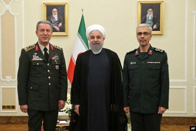 In this photo released by an official website of the office of the Iranian Presidency, President Hassan Rouhani, center, poses for a photo with Turkey's Chief of Staff Gen. Hulusi Akar, left, and Chief of Staff of Iran's Armed Forces, Gen. Mohammad Hossein Bagheri, during their meeting in Tehran, Oct. 2, 2017.