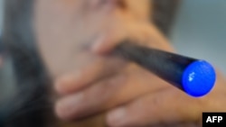 FILE- A woman smokes a "Blu" e-cigarette (electronic cigarette) in Washington, D.C. The number of U.S. youths who have tried e-cigarettes tripled from 2011 to 2013, raising concerns about the potential for a new generation of nicotine addicts, U.S. health authorities said.