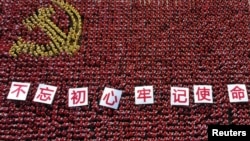 中国浙江省金华市的中共党员手举“不忘初心牢记使命”的标语牌组成中共党旗图案的阵仗。（2019年6月28日）
