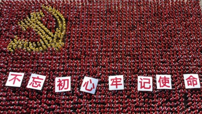 中国浙江省金华市的中共党员手举“不忘初心牢记使命”的标语牌组成中共党旗图案的阵仗。(2019年6月28日)
