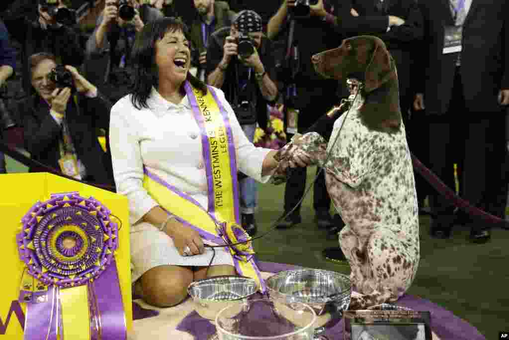 Valerie Nunes-Atkinson and CJ, a German shorthaired pointer, pose for photographers after CJ won best in show at the 140th Westminster Kennel Club dog show at Madison Square Garden in New York, Feb. 16, 2016.