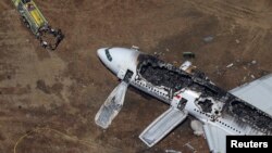 FILE - Rescue officials stand near an Asiana Airlines Boeing 777 plane after it crashed while landing at San Francisco International Airport in California, July 6, 2013. 