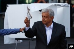 Presidential candidate Andres Manuel Lopez Obrador, of the MORENA party, shows his ballot to the press before casting it during general elections in Mexico City, July 1, 2018.