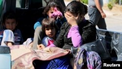 FILE - Civilians, allegedly wounded by Islamic State fighters, wait with relatives to cross into Turkey at the Syrian-Turkish border crossing of Tel Abyad, Syria, June 25, 2015.