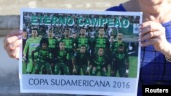 브라질 프로축구팀 샤페코엔시 소속 선수들이 지난 28일 비행기 추락 사고로 사망한 가운데 축구팬이 이들의 사진이 담긴 포스터를 들고 있다.