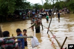 Rohingya Muslims, who crossed over recently from Myanmar into Bangladesh, cross a flooded area to find alternate shelter after their camp was inundated with rainwater near Balukhali refugee camp, Bangladesh, Sept. 19, 2017.
