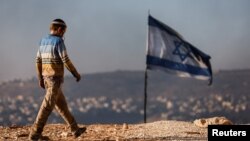 23 Haziran 2021 - Batı Şeria'da Mayıs ayında kurulan İsrail karakolu Givat Eviatar önündeki bayrak ve çevredeki Yahudi yerleşim biriminde yaşayan bir çocuk