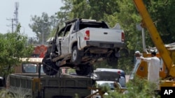 A damaged vehicle that carried military officers is removed from the site of suicide bombing on the outskirts of Fateh Jang, some 36 kilometers (22 miles) southwest of Islamabad, Pakistan, Wednesday, June 4, 2014.