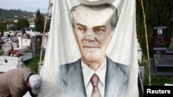 An Albanian communist hangs a banner showing the late communist dictator Enver Hoxha in the public cemetery in Tirana, April 11, 2012.