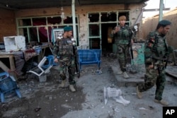 FILE - Afghan security forces inspect damages after clashes between Taliban fighters and Afghan forces in Kandahar Airfield, Afghanistan, Wednesday, Dec. 9, 2015.
