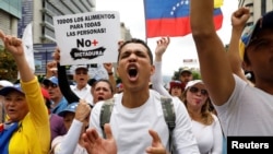 Demonstrators carry a sign – ' All the food for all the people! No more dictatorship' – while rallying against Venezuela's President Nicolas Maduro in Caracas, May 1, 2017.