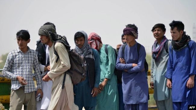 Afghan men wait in queue to cross into Iran at an Afghan-Iran border crossing in Zaranj on Sept. 8, 2021.