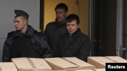Detained opposition activist Konstantin Lebedev (R, front) is escorted out of a building of the Russian Investigative Committee in Moscow, October 17, 2012.