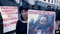 A protester holds up a poster with writing reading in Italian "Justice for Abu Omar" above a picture of Muslim cleric Osama Moustafa Hassan Nasr, also known as Abu Omar, outside Milan's court house while the trial of 26 Americans and seven Italians accused of orchestrating a CIA-led kidnapping of an Egyptian terror suspect Nasr was taking place inside the courtroom, in Milan, Italy, Sept. 23, 2009.