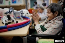A resident claps to call 'AIBO', a pet dog robot at Shin-tomi nursing home in Tokyo, Japan, Feb. 2, 2018.