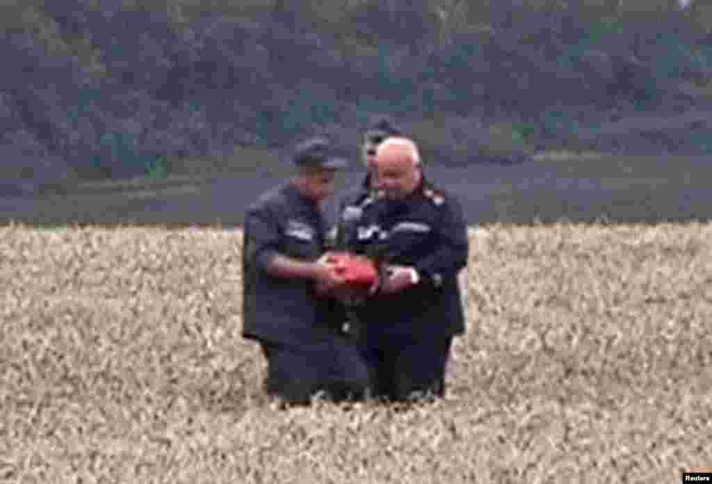 A rescue worker shows a flight data recorder to a colleague at the crash site of Malaysia Airlines Flight MH17 in Hrabove July 18, 2014 in this still image taken from video. Rescue workers have recovered a &quot;black box&quot; flight recorder from the wreckage of the Malaysian airliner.