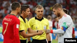 Here, referee Gianluca Rocchi does a pre-match coin toss between Portugal's Cristiano Ronaldo and Spain's Sergio Ramos, June 15, 2018. (REUTERS/Murad Sezer)