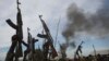 Rebel fighters hold up their rifles as they walk in front of a bushfire in a rebel controlled territory in Upper Nile State, South Sudan, Feb. 13, 2014. 