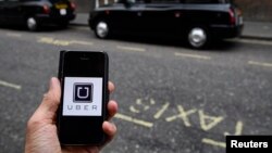 FILE - A photo illustration shows the Uber app logo displayed on a mobile telephone, as it is held up for a posed photograph in central London, Britain October 28, 2016. 