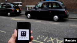 FILE - A photo illustration shows the Uber app logo displayed on a mobile telephone, as it is held up for a posed photograph in central London, Britain October 28, 2016. 