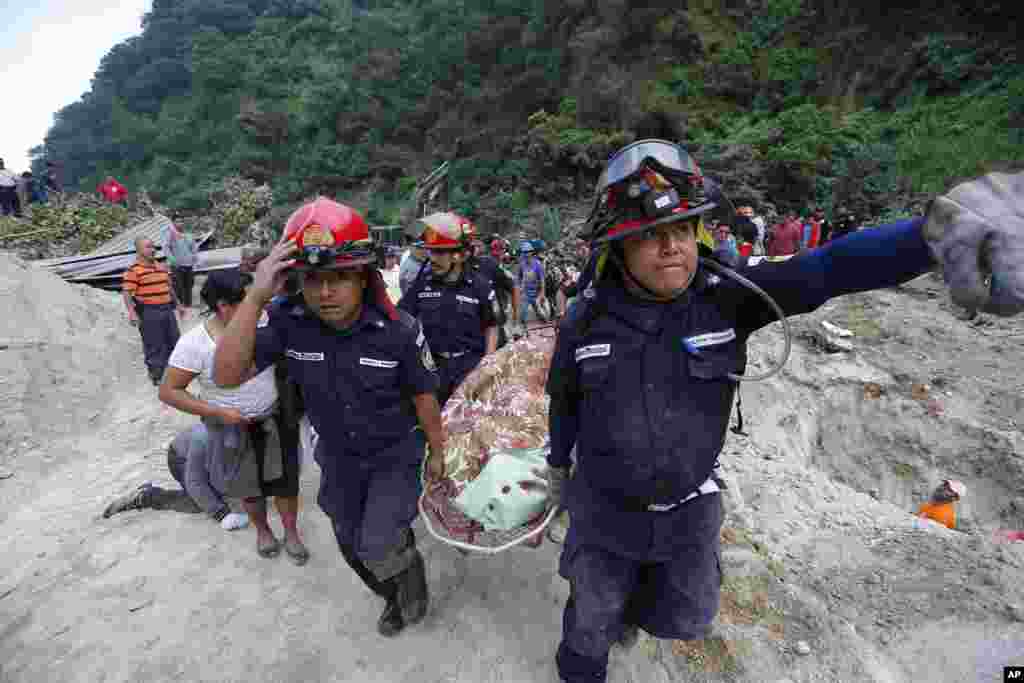 Petugas penyelamat membawa mayat korban longsor di Santa Catarina Pinula, di pinggiran kota Guatemala City. Hujan akhir-akhir ini menyebabkan longsor, dan merusak belasan rumah.