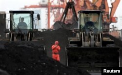 FILE - An employee walks between front-end loaders which are used to move coal imported from North Korea at Dandong port in the Chinese border city of Dandong, Liaoning province, Dec. 7, 2010.