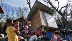 Residents stand amid damaged homes following Typhoon Rai in Talisay, Philippines, Dec. 18, 2021.