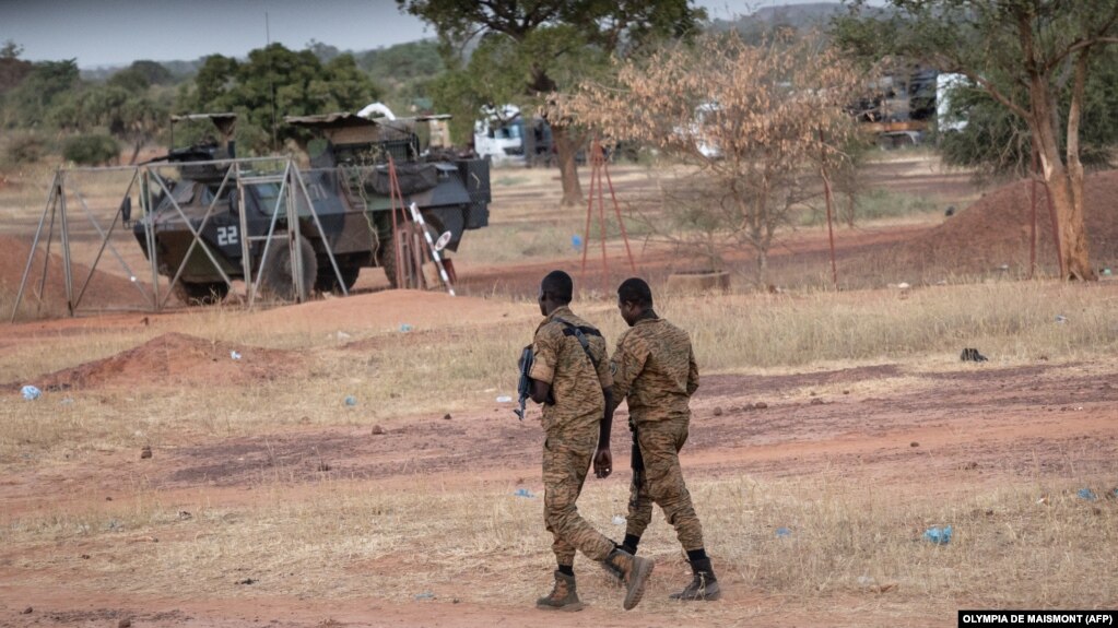 Des officiers de l'armée burkinabé patrouillent près d'un véhicule blindé français stationné à Kaya en transit vers le Niger voisin, le 20 novembre 2021.