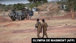 Des officiers de l'armée burkinabé patrouillent près d'un véhicule blindé français stationné à Kaya en transit vers le Niger voisin, le 20 novembre 2021.
