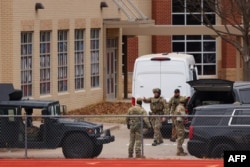 FILE - SWAT team members deploy near the Congregation Beth Israel Synagogue in Colleyville, Texas, some 25 miles (40 kilometers) west of Dallas, Jan. 15, 2022.