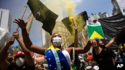 한 여성 시위자가 2일 리우데자네이루에서 열린 대통령 퇴진 촉구 시위에서 브라질 국기를 두른 채 자이르 보우소나루 대통령의 탄핵을 외치고 있다.