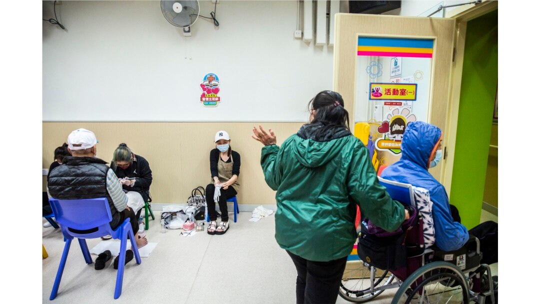 Seorang nenek (kedua dari kanan) berterima kasih dan melambai kepada relawan manikur karena memberikan layanan pedikur gratis kepada orang tua di pusat komunitas untuk orang tua di Hong Kong sebagai bagian dari inisiatif amal, 8 November 2021. (Foto: AFP