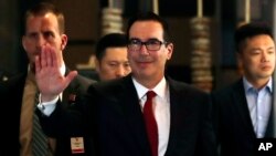 El secetario del Tesoro de EE.UU., Steven Mnuchin, (centro) salua a priodistas a su arribo a un hotel tras reunirse con funcionarios chinos en Beijing, el jueves, 3 de mayo, de 2018.